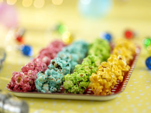 Rader av popcornbollar i fyra olika färger på en bricka